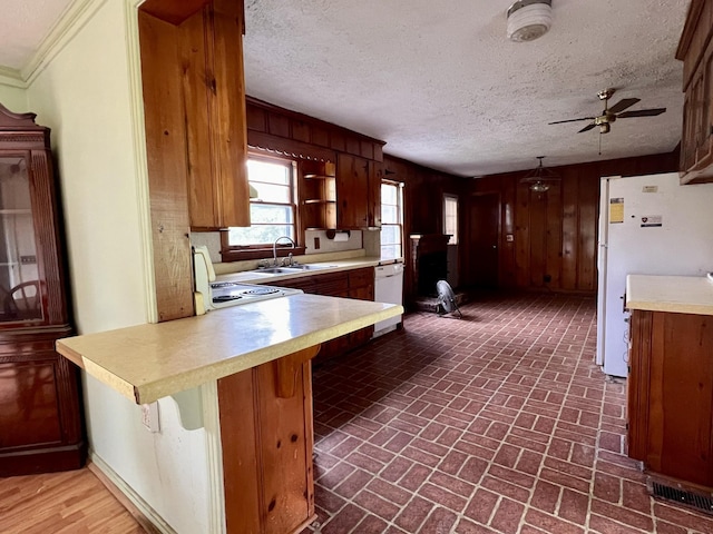 kitchen with kitchen peninsula, a kitchen breakfast bar, white appliances, a textured ceiling, and sink