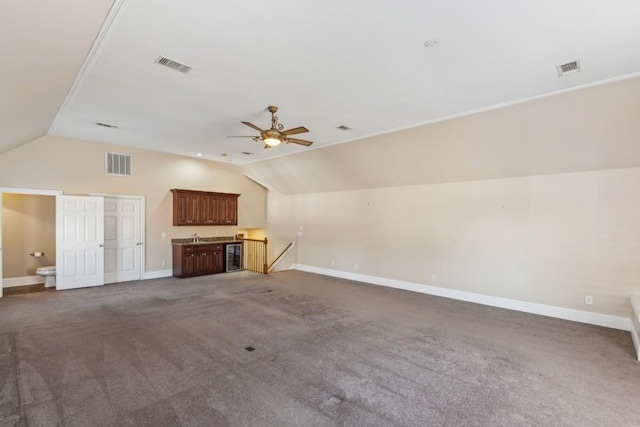 unfurnished living room featuring wine cooler, vaulted ceiling, dark carpet, and ceiling fan