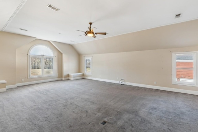 additional living space with carpet flooring, vaulted ceiling, a wealth of natural light, and ceiling fan