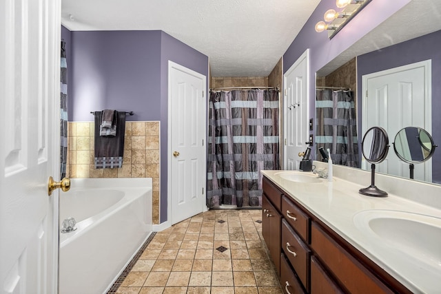 bathroom with a textured ceiling, vanity, and separate shower and tub