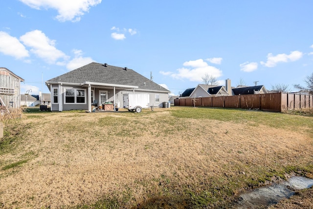 rear view of house featuring central AC unit and a lawn