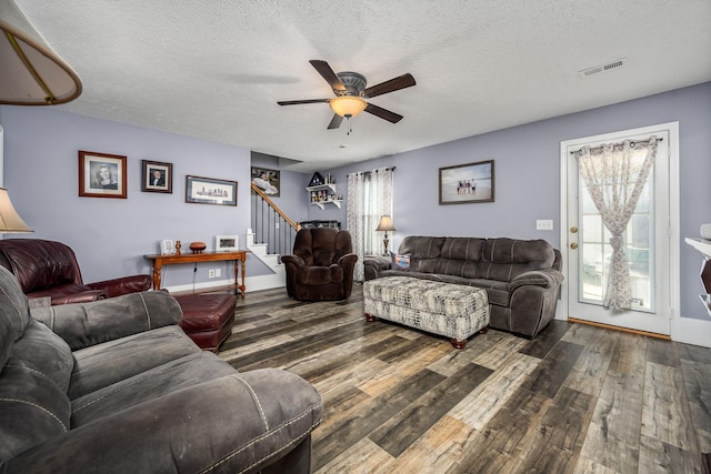 living room featuring a textured ceiling, ceiling fan, and dark wood-type flooring