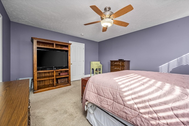 bedroom featuring ceiling fan, light colored carpet, and a textured ceiling