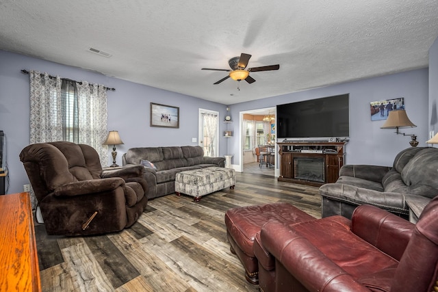 living room featuring hardwood / wood-style flooring, ceiling fan, and a textured ceiling