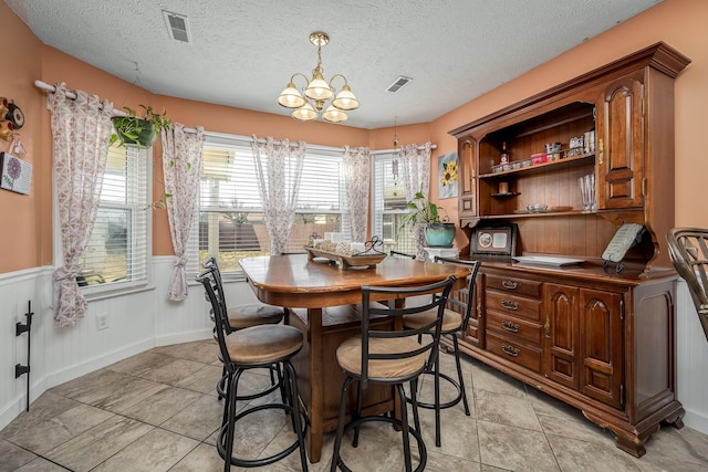 tiled dining room with a textured ceiling and an inviting chandelier