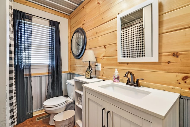 bathroom featuring hardwood / wood-style flooring, vanity, toilet, and wooden walls