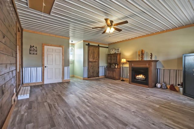 unfurnished living room featuring wood-type flooring, a barn door, and ceiling fan