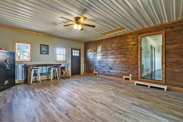 interior space with ceiling fan, hardwood / wood-style flooring, radiator, and wood walls