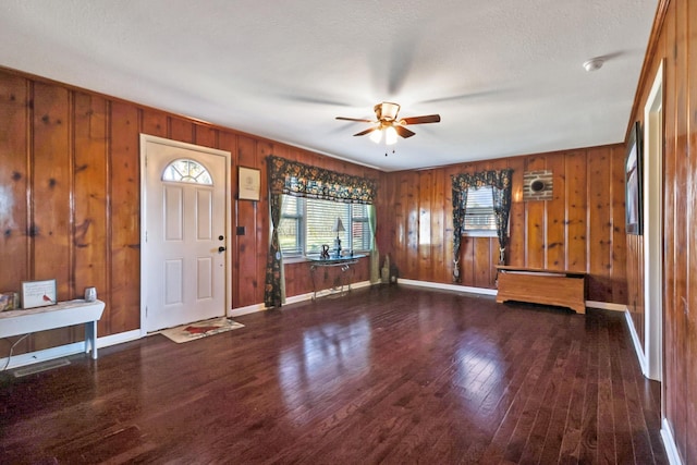 entryway with dark hardwood / wood-style flooring, ceiling fan, and wooden walls