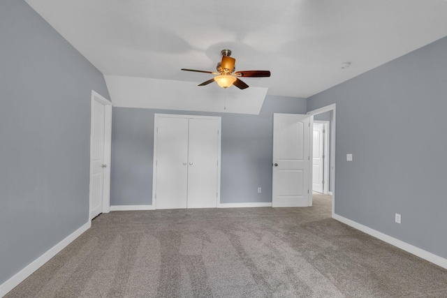 unfurnished bedroom featuring ceiling fan, a closet, carpet floors, and vaulted ceiling