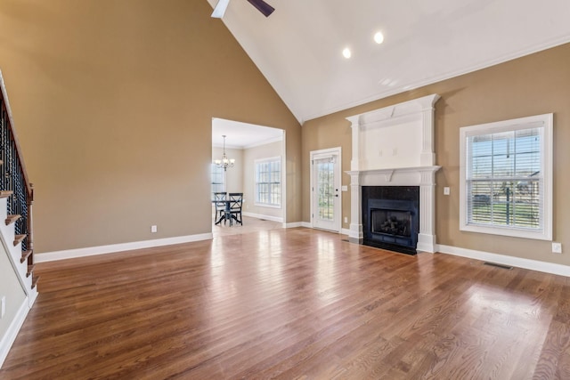 unfurnished living room featuring ceiling fan with notable chandelier, crown molding, high vaulted ceiling, and hardwood / wood-style floors