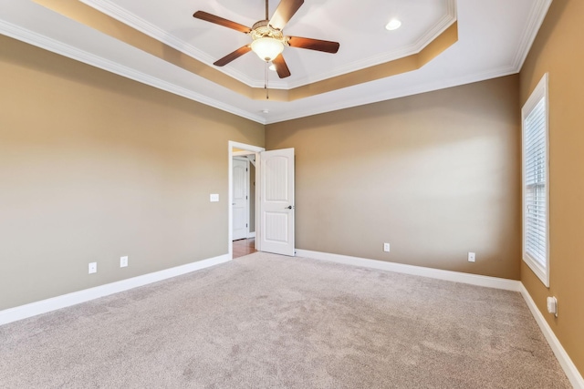 carpeted empty room featuring crown molding, a tray ceiling, and ceiling fan