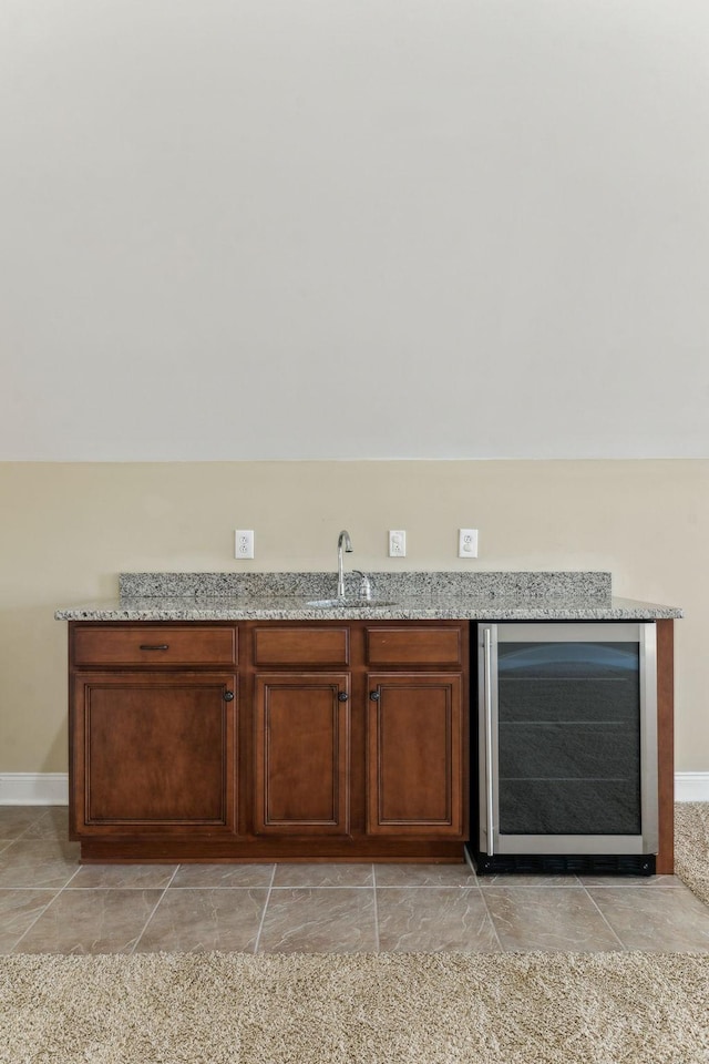 bar with vaulted ceiling, light stone countertops, sink, and beverage cooler