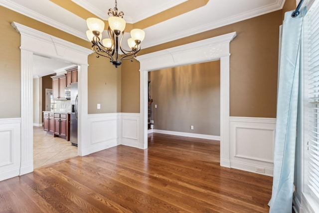 unfurnished dining area with crown molding, a chandelier, and hardwood / wood-style flooring