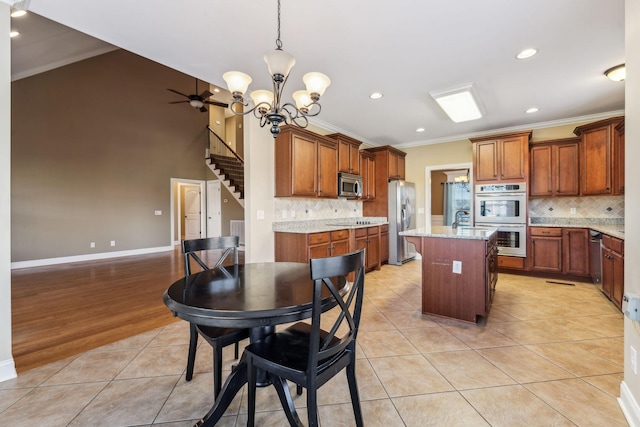 kitchen with light tile patterned floors, stainless steel appliances, light stone counters, tasteful backsplash, and a kitchen island