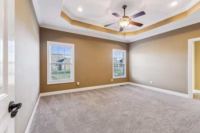 carpeted spare room with ornamental molding, ceiling fan, and a tray ceiling