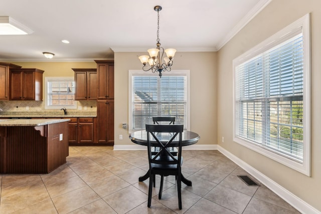 dining area with an inviting chandelier, light tile patterned floors, plenty of natural light, and ornamental molding