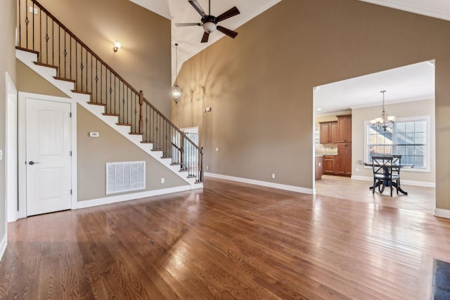 unfurnished living room with hardwood / wood-style floors, crown molding, a high ceiling, and ceiling fan with notable chandelier