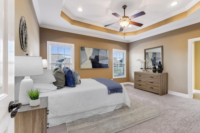 carpeted bedroom with a tray ceiling, ornamental molding, and ceiling fan