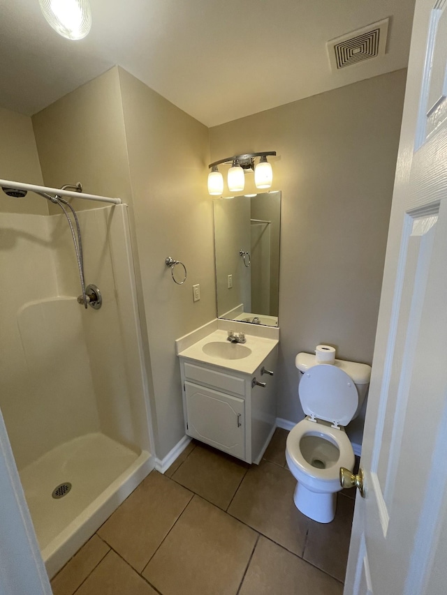 bathroom featuring tile patterned flooring, vanity, toilet, and walk in shower