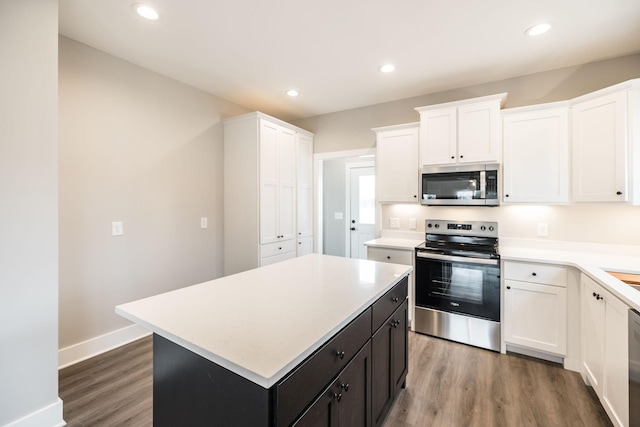 kitchen featuring hardwood / wood-style flooring, a kitchen island, white cabinetry, and appliances with stainless steel finishes