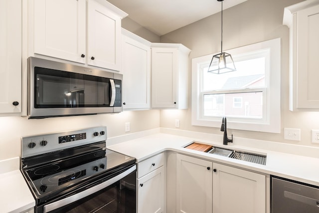 kitchen featuring white cabinetry, sink, stainless steel appliances, and decorative light fixtures