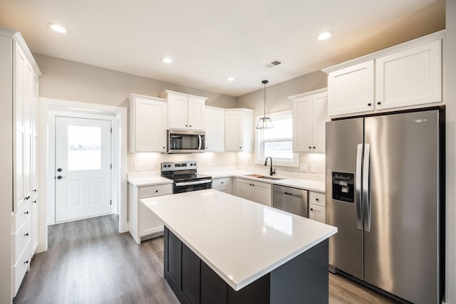 kitchen with white cabinets, a kitchen island, pendant lighting, and appliances with stainless steel finishes