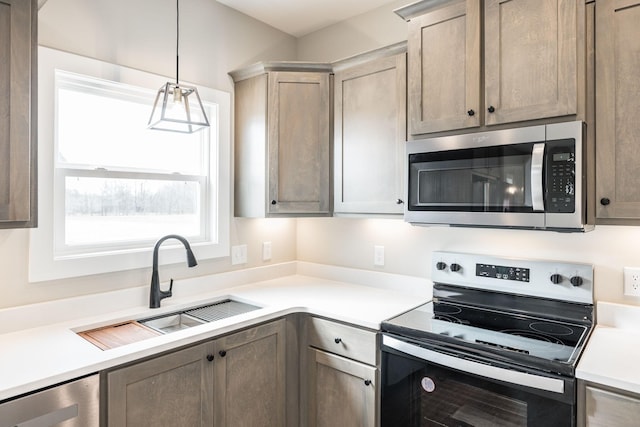 kitchen with decorative light fixtures, stainless steel appliances, beverage cooler, and sink