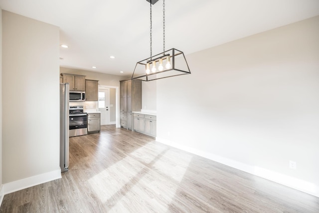 interior space with pendant lighting, stainless steel appliances, and light hardwood / wood-style floors