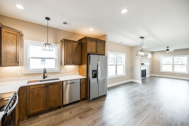 kitchen with hanging light fixtures, sink, ceiling fan, appliances with stainless steel finishes, and wood-type flooring