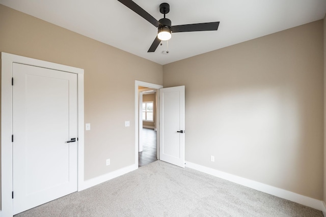 unfurnished bedroom featuring a closet, light colored carpet, and ceiling fan