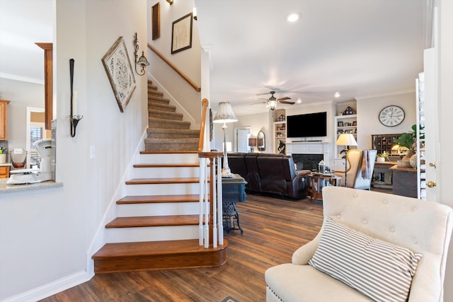 stairway featuring hardwood / wood-style floors, ceiling fan, built in features, and ornamental molding