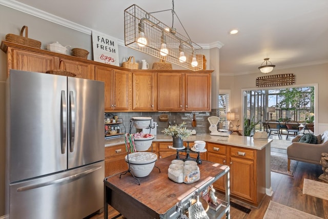 kitchen with decorative backsplash, stainless steel fridge, crown molding, pendant lighting, and dark hardwood / wood-style floors