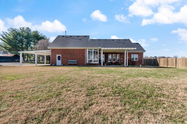 back of property with a carport and a yard