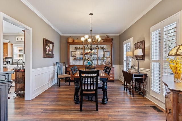 dining area featuring crown molding, dark hardwood / wood-style flooring, and an inviting chandelier