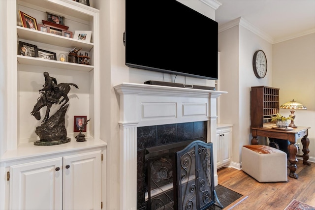 living room with ornamental molding, a tile fireplace, and light hardwood / wood-style flooring