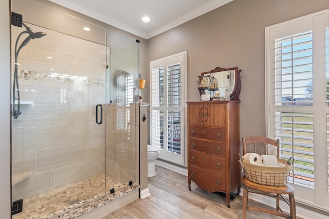 bathroom with a wealth of natural light, a shower with door, wood-type flooring, and ornamental molding