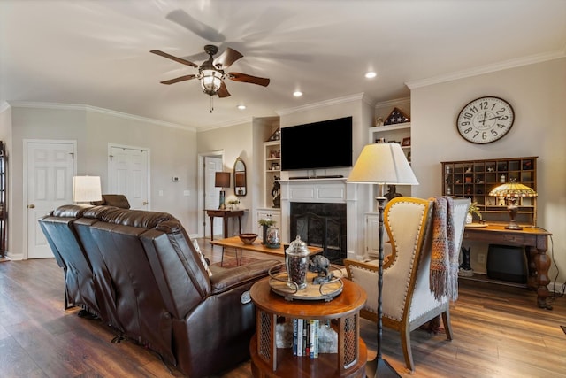 living room featuring a high end fireplace, ornamental molding, built in shelves, ceiling fan, and wood-type flooring