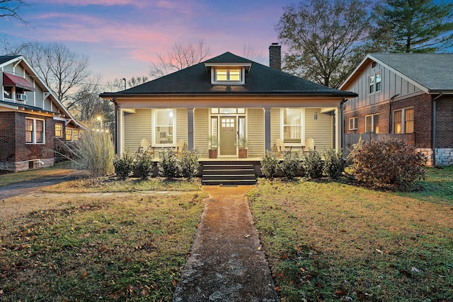 bungalow-style home featuring covered porch and a yard