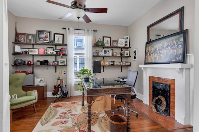 home office featuring a fireplace, hardwood / wood-style floors, and ceiling fan