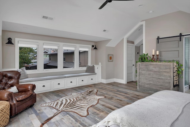 living room with a barn door, light hardwood / wood-style floors, and lofted ceiling