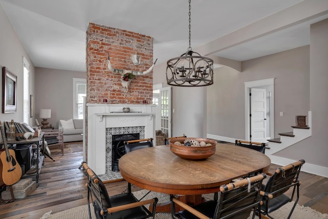 dining space featuring a fireplace, dark hardwood / wood-style floors, and a chandelier