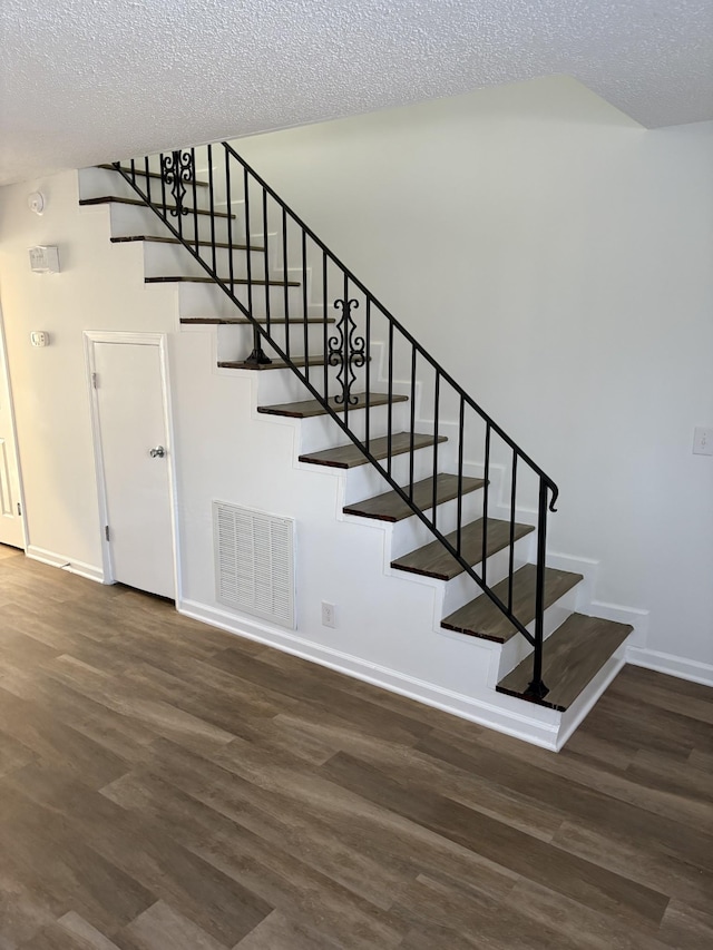 staircase featuring hardwood / wood-style floors and a textured ceiling