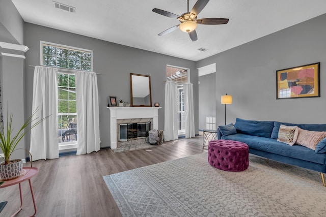 living room with a premium fireplace, ceiling fan, and hardwood / wood-style flooring