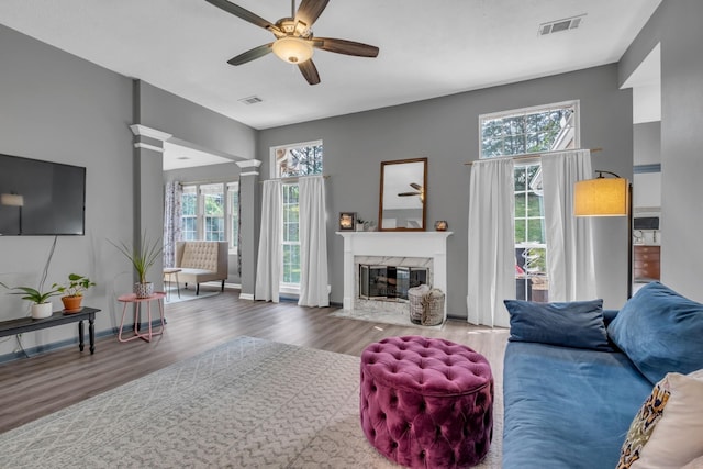 living room with hardwood / wood-style floors, ceiling fan, a premium fireplace, and ornate columns