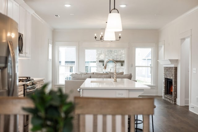 kitchen featuring white cabinets, sink, ornamental molding, decorative light fixtures, and a chandelier