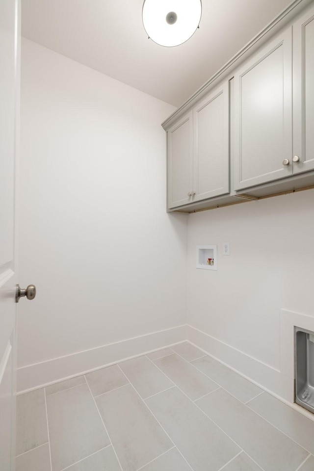 laundry area with washer hookup, light tile patterned flooring, and cabinets