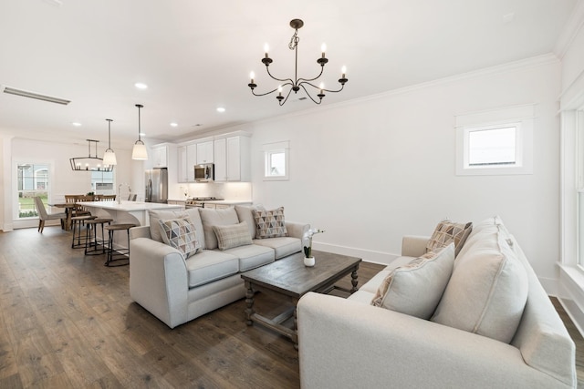 living room featuring a wealth of natural light, an inviting chandelier, dark hardwood / wood-style floors, and ornamental molding