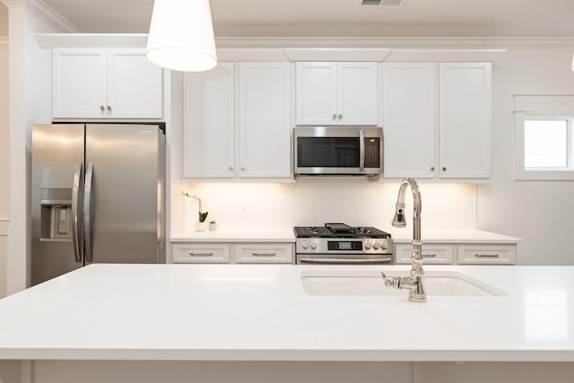 kitchen featuring sink, crown molding, decorative backsplash, appliances with stainless steel finishes, and white cabinetry