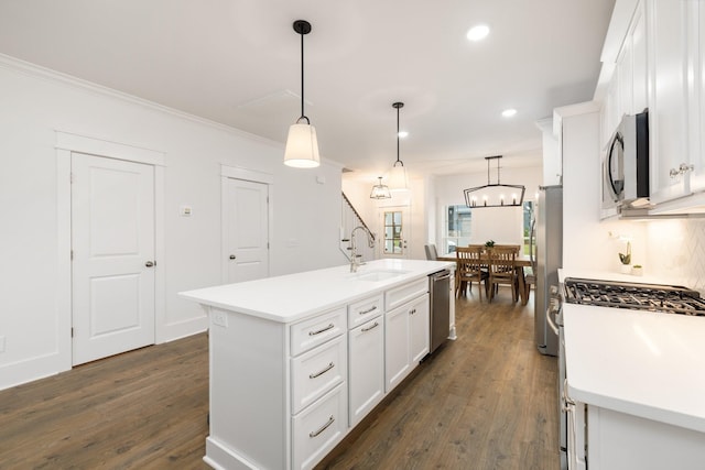 kitchen featuring appliances with stainless steel finishes, sink, decorative light fixtures, white cabinets, and an island with sink